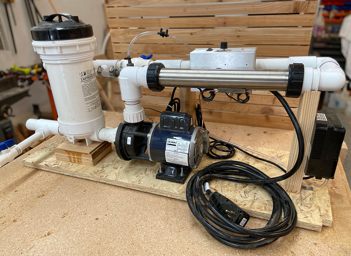 Spa-grade heating system with filter, circulation pump, and heater controller assembled on a workbench